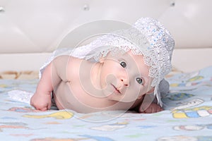 Cute newborn baby is lying on his stomach, looking at the camera with wide-open eyes in surprise