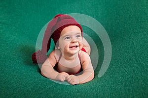 Cute newborn baby in the red hat. Happy baby on a green background. Closeup portrait of newborn baby. Baby goods packing template.