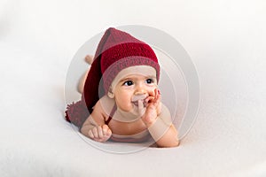 Cute newborn baby in the red hat. Happy baby on a white background. Closeup portrait of newborn baby. Baby goods packing template.