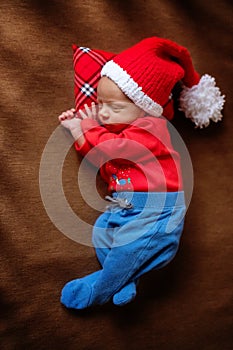 Cute newborn baby in Santa hat. Sleeping baby on a dark background. Closeup portrait of newborn baby. Baby goods packing template.