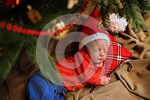 Cute newborn baby in Santa hat. Sleeping baby under the fir-tree. Closeup portrait of newborn baby. Baby goods packing template. N