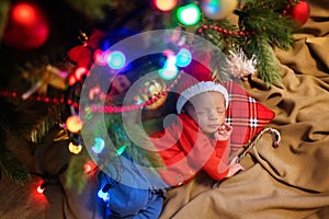 Cute newborn baby in Santa hat. Sleeping baby under the fir-tree. Closeup portrait of newborn baby. Baby goods packing template. N