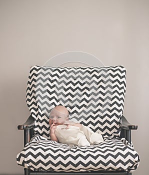 Cute newborn baby sitting in the big chair