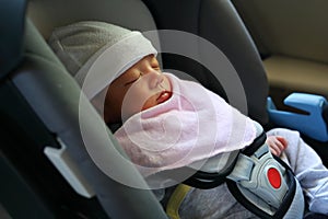 Cute newborn baby sleeping in car seat safety belt lock