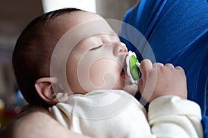 Cute newborn baby sleeping in father arms close up. A loving father carries her newborn baby at home. portrait of a