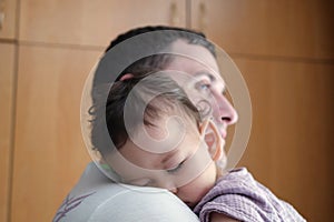 Cute newborn baby sleeping in father arms close up. A loving father carries her newborn baby at home. portrait of a