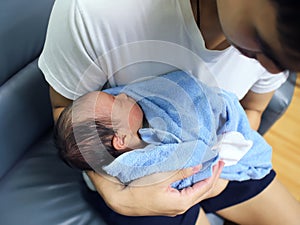 Cute newborn baby sleeping in hands of parents.