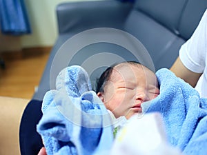 Cute newborn baby sleeping in hands of parents.