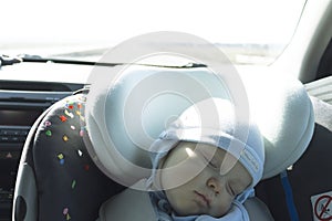 Cute newborn baby sleeping in modern car seat. Child new born traveling safety on the road. Safe way to travel fastened