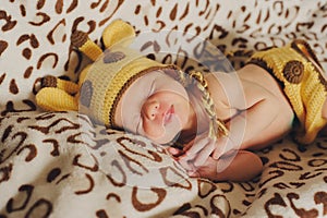 Cute newborn baby sleeps in a hat giraffe on the spotted background.