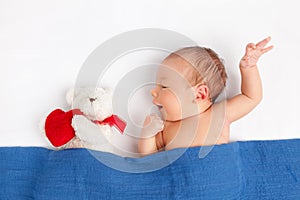 Cute newborn baby with a teddy bear under a blanket