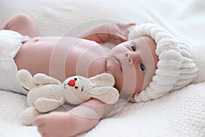 Cute newborn baby with toy in knitted hat on plaid