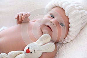 Cute newborn baby with toy in knitted hat on plaid, closeup