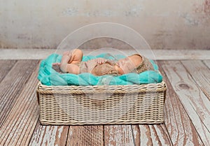 Cute newborn baby on turquoise blanket in cot