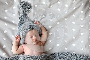 Cute newborn baby in warm hat sleeping on bed. Space for text