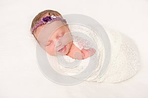 Cute newborn in headband with flowers smiling asleep