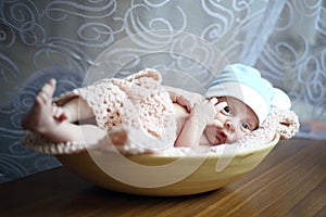Cute newborn sleeping in a beige plate
