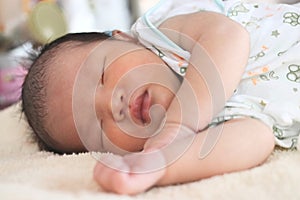 Cute newborn tiny Asian baby sleeping on the bed