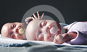 Cute newborn twins boy and girl are lying on the bed against a dark background. With toning and blurring. photo