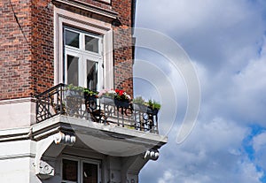 Cute old balcony with flowers and a window in an old blick house.