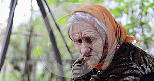 A cute old woman sits on a swing.