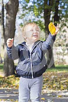 Cute one year old baby girl playing with a leaf in a park