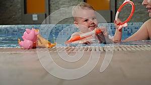 Cute one-year-old baby playing with toys in the pool.