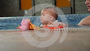 Cute one-year-old baby playing with toys in the pool.