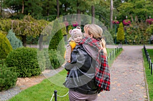Cute one-year-old child in the arms of his mother. The family walks in the autumn park. A young son is in the arms of