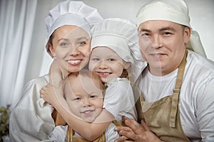 Cute oriental family with mother, father, daughter, son cooking in the kitchen on Ramadan, Kurban-Bairam, Eid al-Adha