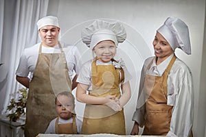 Cute oriental family with mother, father, daughter, son cooking in kitchen on Ramadan, Kurban-Bairam, Eid al-Adha. Funny