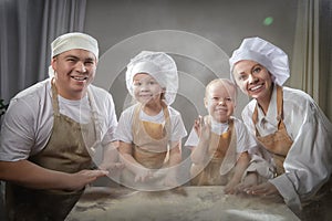 Cute oriental family with mother, father, daughter, son cooking in kitchen on Ramadan, Kurban-Bairam, Eid al-Adha. Funny