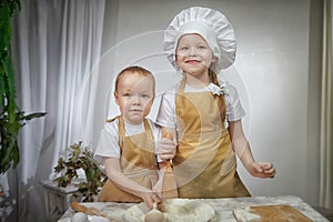 Cute oriental family with small brother and sister cooking in kitchen on Ramadan, Kurban-Bairam, Eid al-Adha. Funny