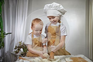 Cute oriental family with small brother and sister cooking in kitchen on Ramadan, Kurban-Bairam, Eid al-Adha. Funny