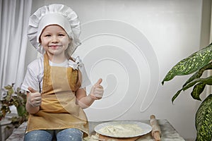 Cute oriental girl cooking in kitchen on Ramadan, Kurban-Bairam, Eid al-Adha. Funny female child at cook photo shoot