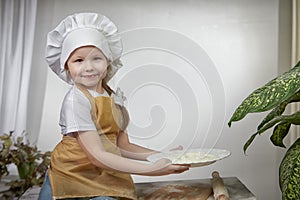 Cute oriental girl cooking in kitchen on Ramadan, Kurban-Bairam, Eid al-Adha. Funny female child at cook photo shoot