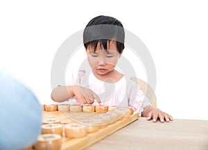 The cute oriental girl is seriously playing Chinese chess with her opponent