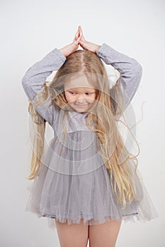 Cute orphan girl stands and holds her hands over her head in the form of a house, dreaming of an apartment, on a white background