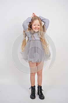 Cute orphan girl stands and holds her hands over her head in the form of a house, dreaming of an apartment, on a white background