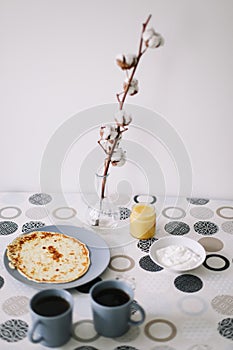 Stack of delicious homemade pancakes on plate with honey, sour cream and tea. Breakfast. Rustic style, close up top view. Flat lay