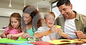 Cute parents and children doing arts and crafts at kitchen table