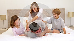 Cute parents and children lying on bed messing around