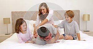 Cute parents and children lying on bed messing around