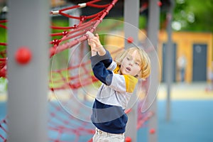 Cute perky preschooler boy having fun on outdoor playground. Spring or summer or autumn active sport leisure for kids. Modern