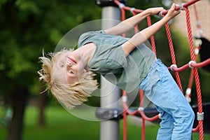 Cute perky preschooler boy having fun on outdoor playground. Spring or summer or autumn active sport leisure for kids. Outdoor