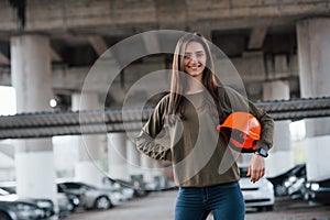 Cute person. Portrait of beautiful young woman with safety helmet standing under the bridge