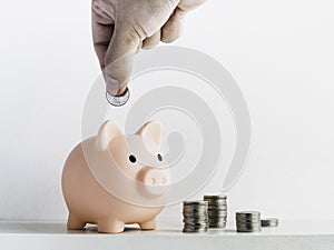 Cute piggy bank, pink color with stacks of coins isolated on white background.