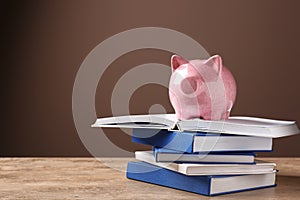 Cute piggy bank on stack of books against color background