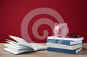 Cute piggy bank on stack of books against color background