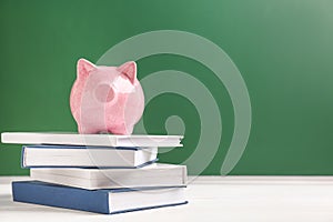 Cute piggy bank on stack of books against color background